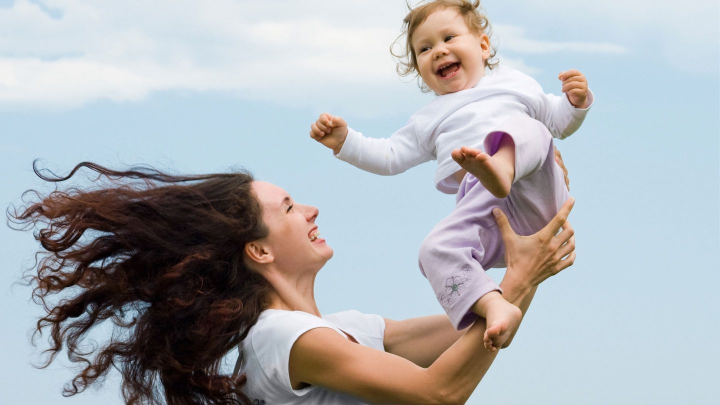 Une maman avec un grand sourire fait sauter son enfant dans ses bras