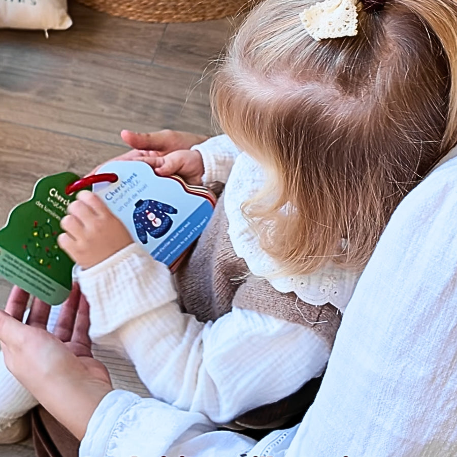 Une maman et sa fille jouent a cherchons ensemble dans un decor de Noel